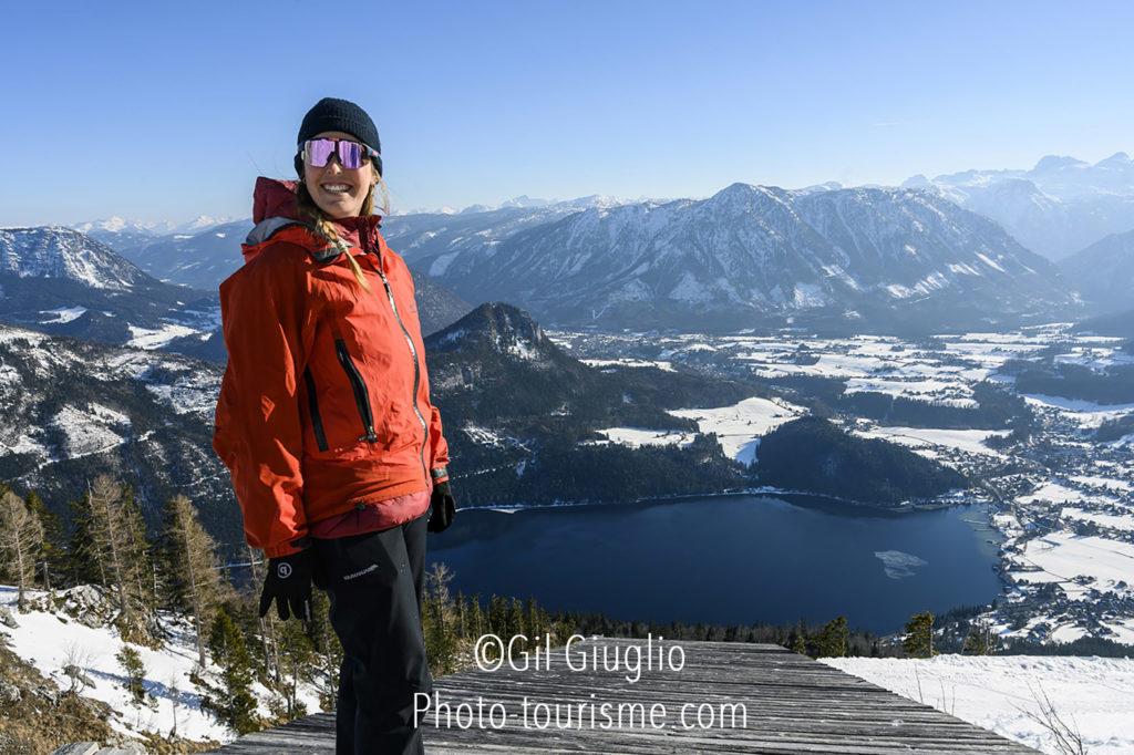 Personnage souriant qui domine une vallée avec un lac en hiver