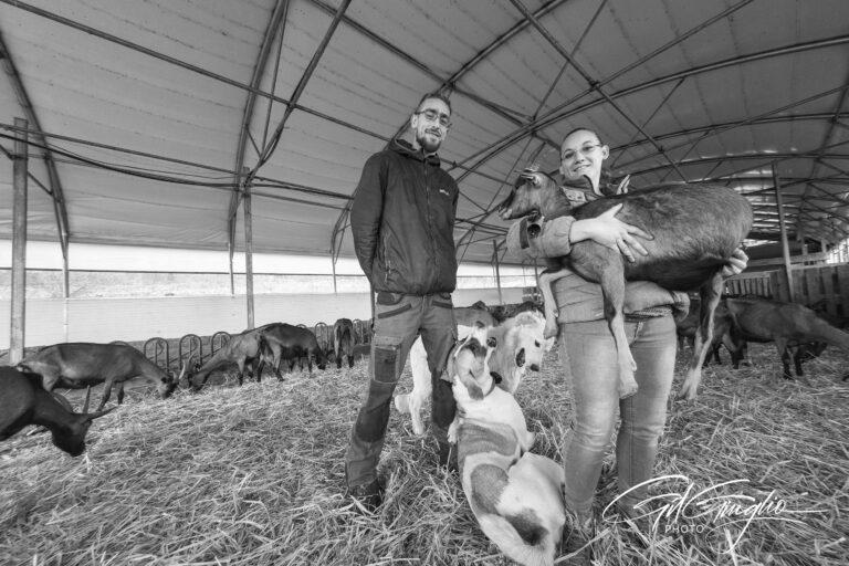 Homme, chiens et femme avec une chèvre dans les bras