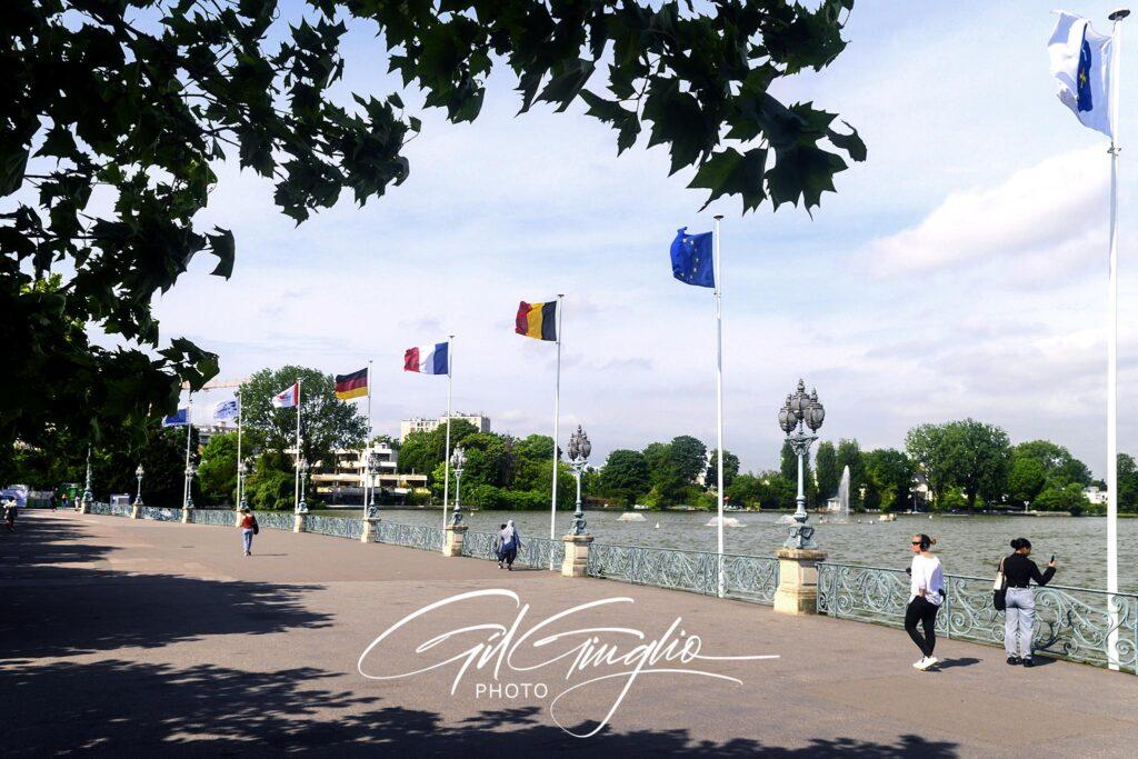 Jetée avec drapeaux et passants devant le lac