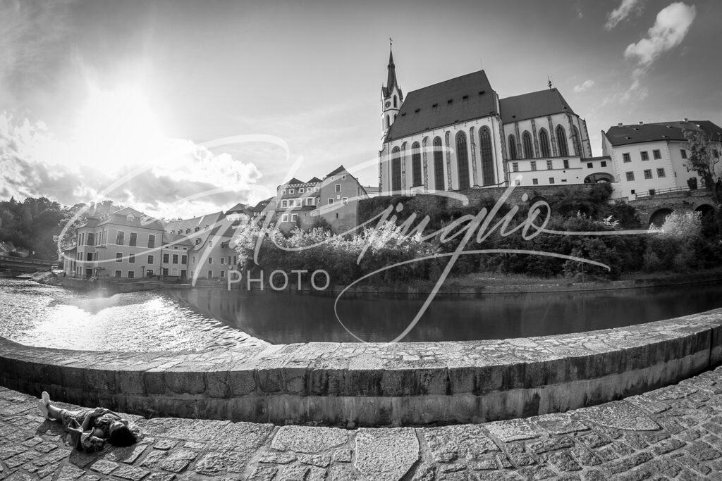 Personnage allongé devant rivière et église