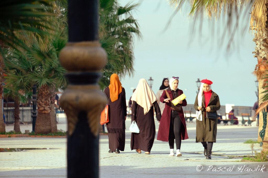 Femmesqui marvhent dans la rue et poteau de lampadaire au premier plan