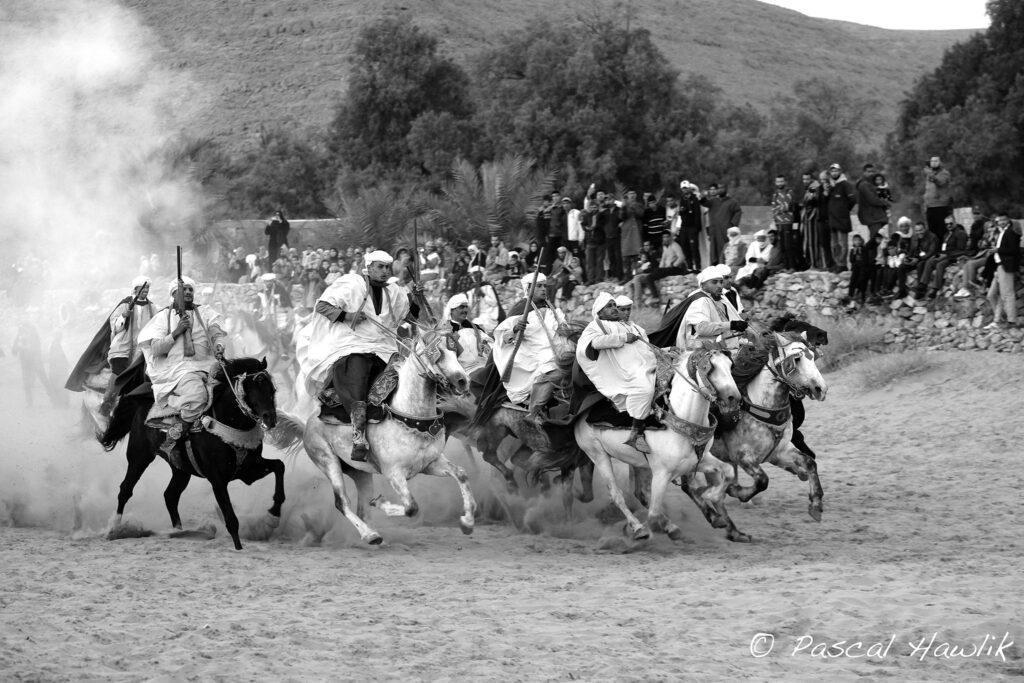 Photo noir et blanche d'hommes à cheval pour cérémonie fantasia