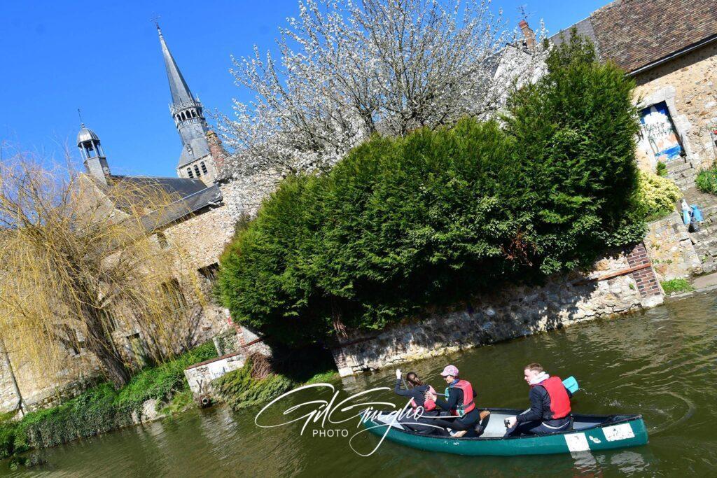 Clocher, rivière, village et personnages dans canoë